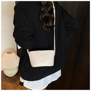 Detail view of cream white bucket bag featuring litchi texture and fashion chic lettering