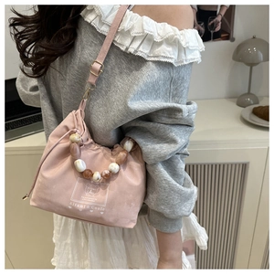 Detailed view of pink beaded handbag with printed logo and adjustable shoulder strap