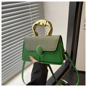 Detail of green crossbody bag featuring houndstooth flap and golden metal handle