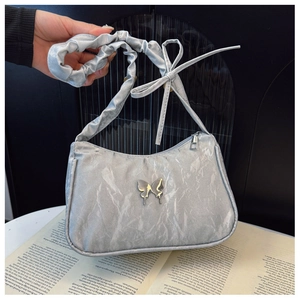 Detail of silver pleated shoulder bag with metallic butterfly and satin marble texture