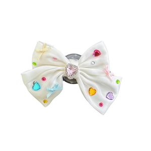 Sparkling DIY bow phone grip with pink heart gemstone and colorful rhinestones on white