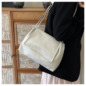 Detail showing creamy white textured fabric and silver chain strap on this shoulder bag