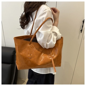 Side view of large vintage brown leather tote bag with tassel worn on shoulder by model