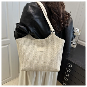 Close-up of beige woven tote bag featuring a leather strap and Fashion label detail