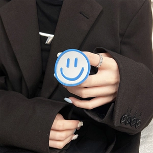 Close-up of a blue and white smiley face phone socket holder held by a hand