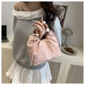 Detail of pink faux suede drawstring bucket bag with decorative marble bead handle
