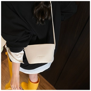 Detail of lychee pattern beige bucket bag with embossed logo and slim leather strap