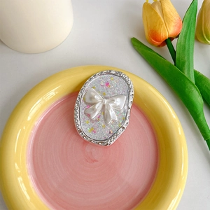 Nahaufnahme der rosa Glitzer-Bogen-Handyhalterung auf einem Deko-Tablett mit Tulpen