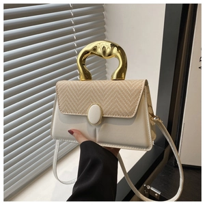 Detail of woven straw flap and organic wave-shaped golden metal handle on handbag