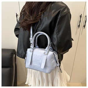 Detailed view of light blue leather boston bag with embossed logo and silver hardware
