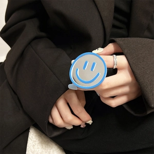 Close-up of a blue circular phone grip with smiley face mirror held by a model