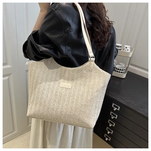 Détail du tissage en paille chevrons et écusson en cuir sur le sac fourre-tout beige