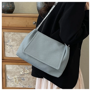 Close-up of light blue tweed shoulder bag showing woven texture and silver chain strap