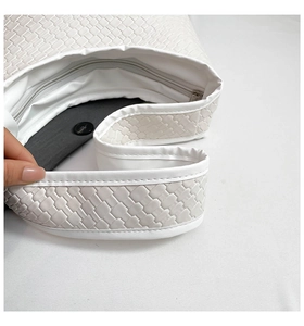 Close-up of white woven leather bucket bag featuring zipper and magnetic snap closure
