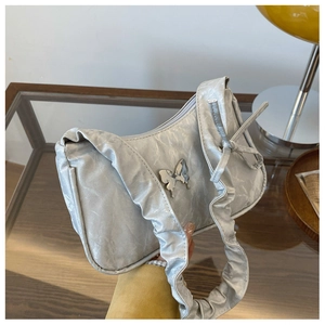Detail of silver pleated shoulder bag with metallic butterfly clasp and ruched strap