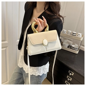Detail of elegant beige patchwork handbag with stylish gold metal U-shaped handle