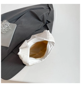 Macro detail of white woven tote bag with silver zipper and spacious interior compartment