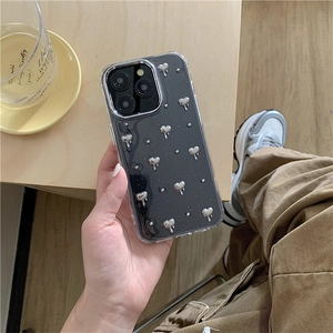 Détail de la coque iPhone avec paillettes noires et breloques en forme de cœur argenté