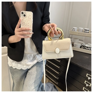 Detail of cream leather handbag with beige straw patchwork and gold U-shaped metal handle