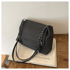 Detail of black textured crossbody bag with classic chain strap on a vintage book