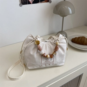 Fashionable beige drawstring bucket bag with colorful marble bead handle and leather strap