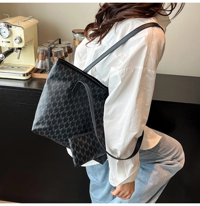 Détail d'un sac cabas noir vintage avec imprimé M gris présenté dans un décor de café chic