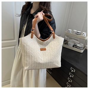 Detailed view of beige woven tote bag with brown fashion leather patch and leather straps