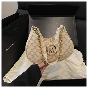 Detail of monogram M canvas hobo bag with gold chain strap on silk fabric backdrop