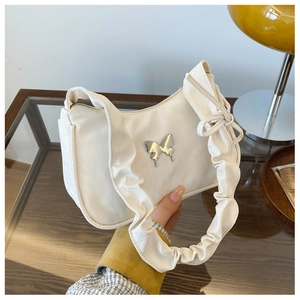 Detail of white hobo bag with silver butterfly ornament and ruffled shoulder strap