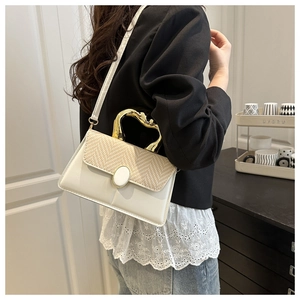 Fashionable crossbody bag with straw-weave flap and unique gold metal handle on model
