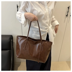 Close-up of a large dark brown tote bag in glossy faux leather with shoulder straps