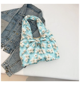 Close-up of light blue fabric bag with white floral embroidery and a large bow