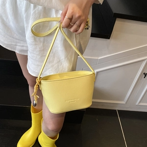 Fashionable bright yellow lychee pattern bucket bag with thin shoulder strap on model