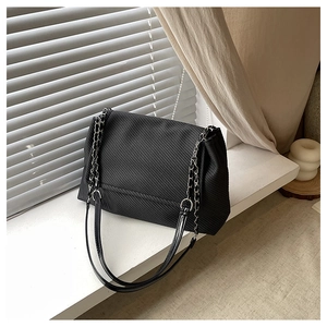 Detail of black corduroy shoulder bag with silver chain strap and flap closure