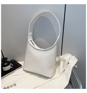 Detail of white woven texture on a minimalist hobo bag styled on a white blazer