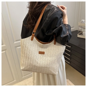 Detailed close-up of woven tote bag texture with brown leather fashion label