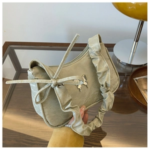 Close-up of sage green ruched handbag featuring a silver butterfly buckle and bow