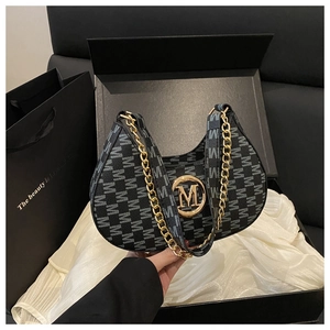 Detail view of black canvas crescent bag with golden M-buckle in a premium gift box