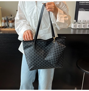 Détail d'un sac cabas noir à motif lettres M et pochette porté par un mannequin