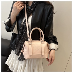 Close-up of pink faux leather pillow bag with embossed text and top handles