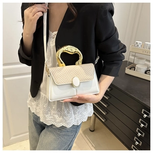 Detail of elegant white leather handbag with gold handle and woven texture detail