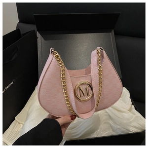 Detail of pink crescent bag with golden M buckle and chain in luxury gift packaging