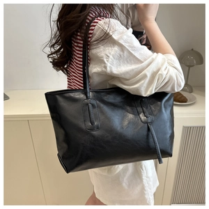 Detail view of large black minimalist tote bag with fine stitching on shoulder strap