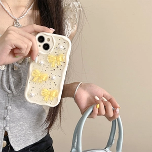 Detail der cremefarbenen iPhone-Hülle mit gelben 3D-Schleifen, Perlen und Goldglitzer