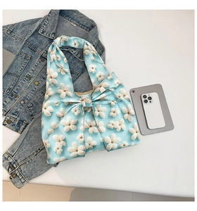 Close-up of light blue floral satin tote bag featuring a decorative large bow detail