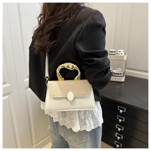 Detailed side view of a white leather and straw patchwork handbag with a gold metal handle