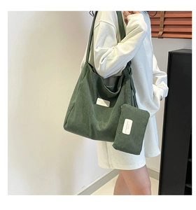 Detailed macro view of dark green corduroy tote bag showing ribbed texture and tag