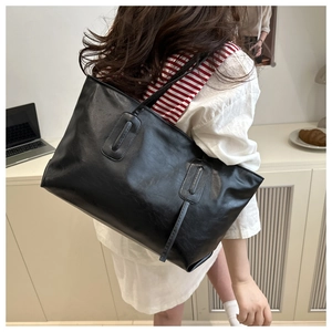 Detailed side view of black large leather tote bag with long shoulder straps for daily commute
