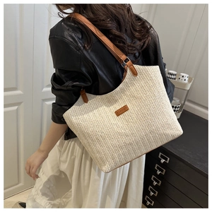 Detail of woven tote bag showing V-pattern texture and brown leather shoulder straps