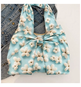 Close-up of light blue floral canvas bag with a large bow and denim jacket background